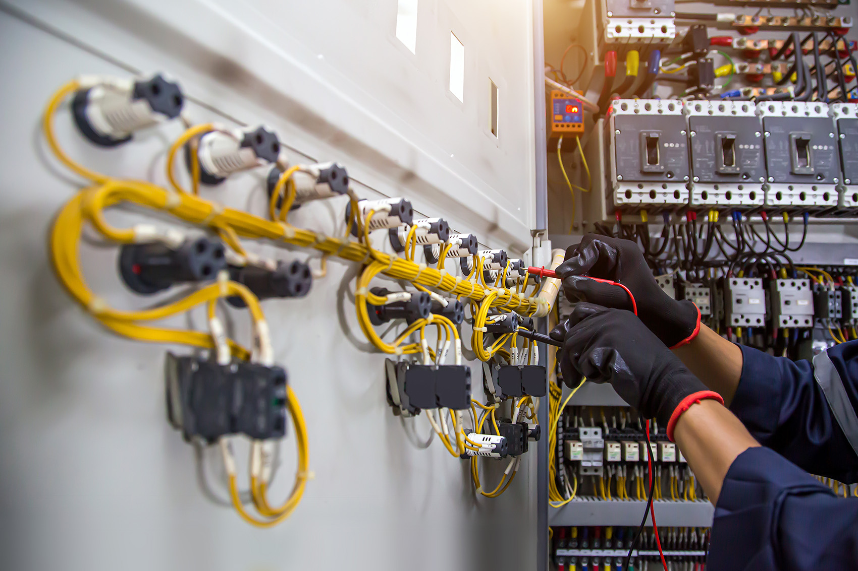 Elektriker prüft Leitungen und Anschlüsse im Schaltschrank – präzise Elektroinstallation.