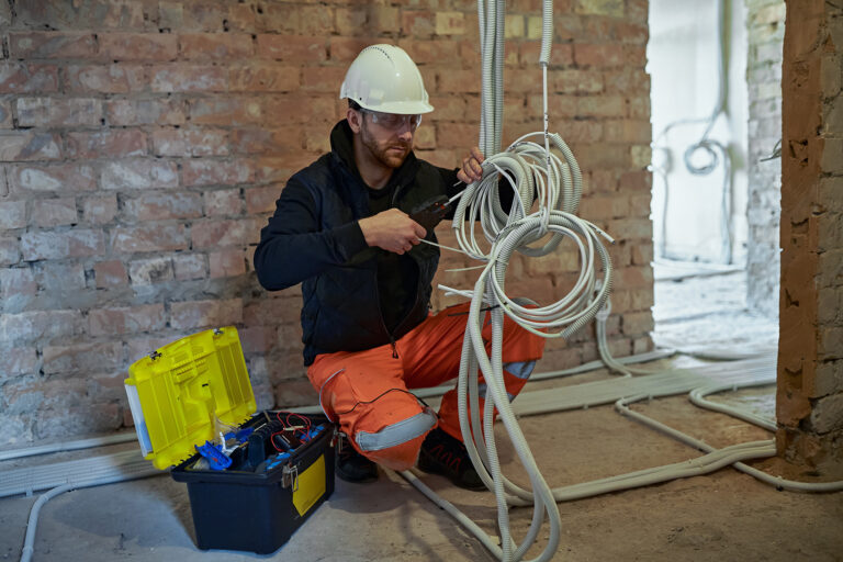 Elektriker verlegt Kabel in einem Neubau